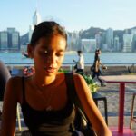 Woman sitting at outdoor cafe with city skyline background