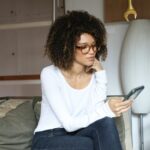 woman in white long sleeve shirt and blue denim jeans sitting on bed